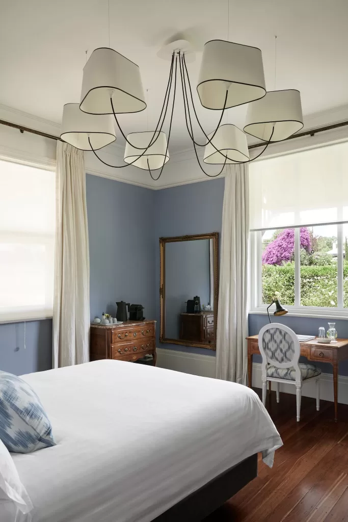 Elegant guest room with blue walls, vintage furniture and garden view at Le Mas Barossa