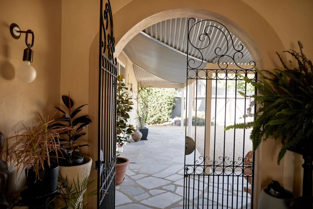 Wrought iron gate and curved archway opening to a stone path at Le Mas Barossa