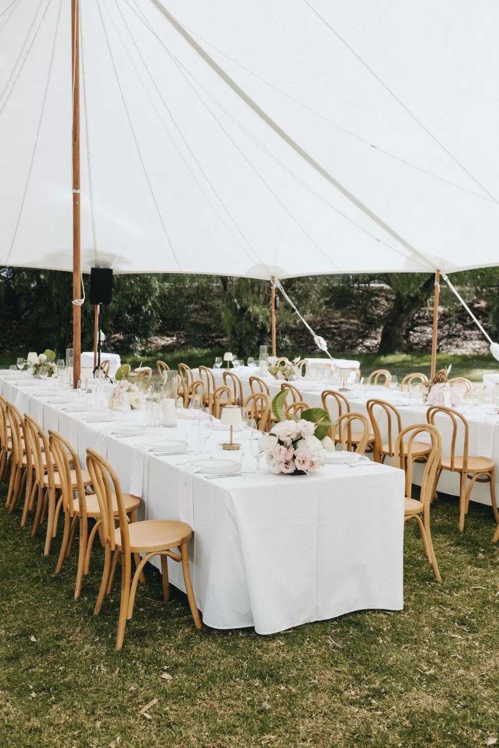 Elegant long tables under a white tent at Le Mas Barossa, styled with soft pink and white florals.