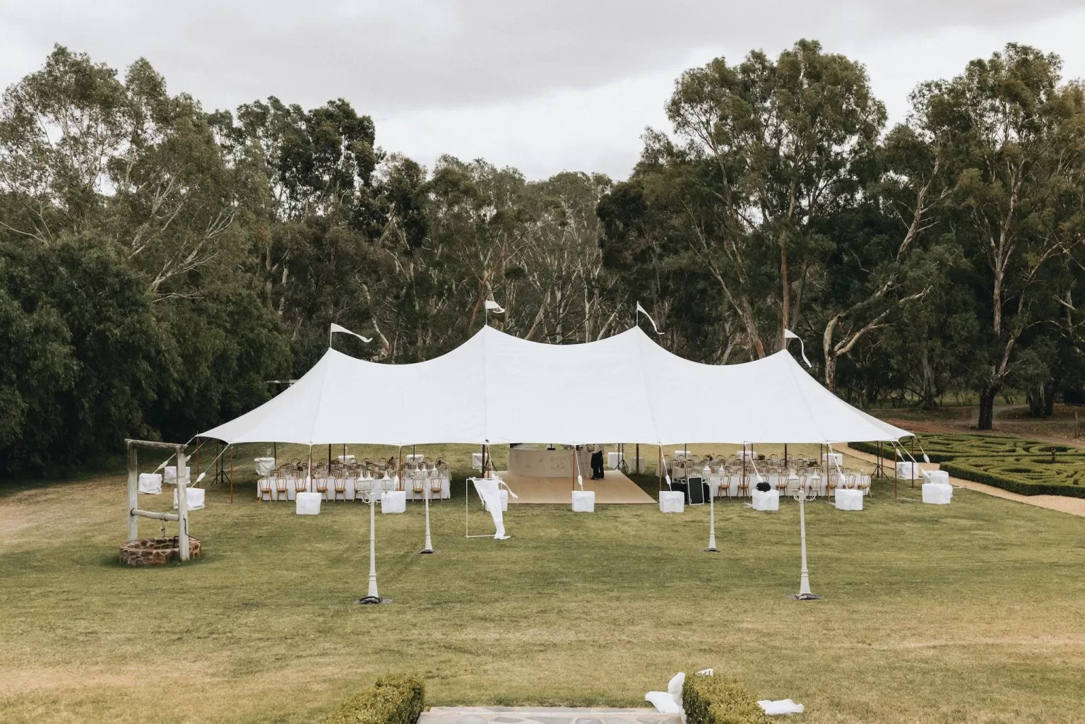 Wide shot of a white marquee tent set up for a garden wedding reception at Le Mas Barossa, surrounded by trees and lawn.