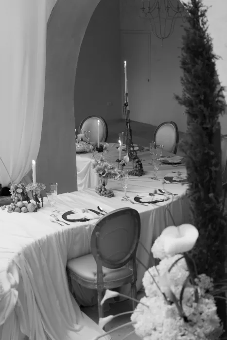 Candlelit wedding dining area under arches at Mas Torroella, styled with trailing greenery and fruit accents.