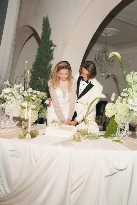 Bride and groom cutting their wedding cake at Mas Torroella surrounded by white flowers and candlelight.