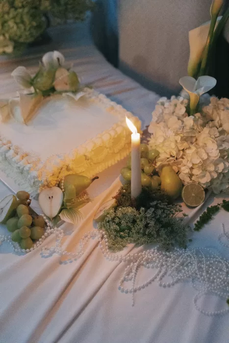 Candlelit cake table at Mas Torroella decorated with fruit, flowers, and pearl strands for a romantic evening look.