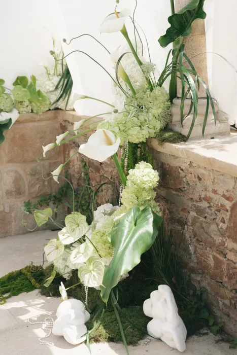 Lush green and white ceremony florals with calla lilies and moss at Mas Torroella.