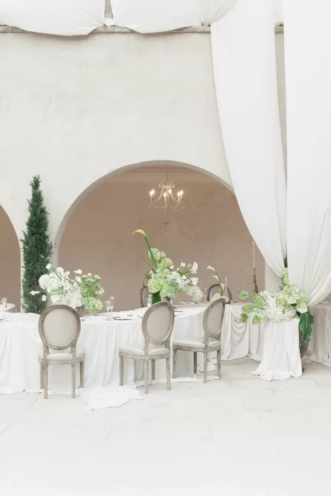 Wedding reception setup at Mas Torroella with billowing drapes, curved banquet tables, and fresh green arrangements.