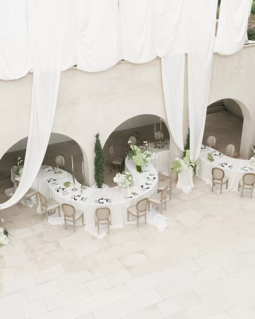 Overhead view of elegant U-shaped reception table setup with white drapes at Mas Torroella.