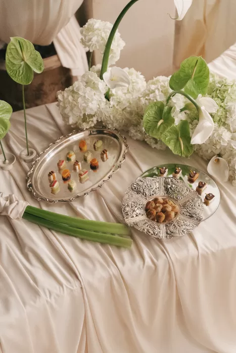 Sophisticated canapé display on silver platters surrounded by white hydrangeas at Mas Torroella wedding reception.