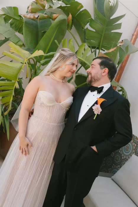 Bride and groom gazing at each other under tropical plants at Masia Cabellut