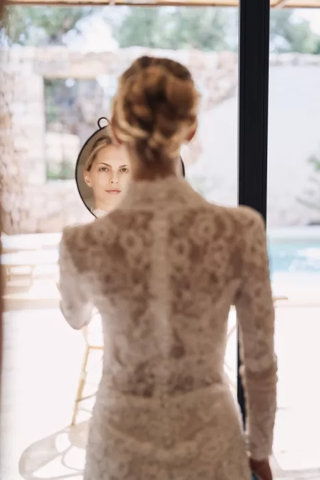 Bride in lace dress reflected in mirror during getting ready at Masseria Calderisi