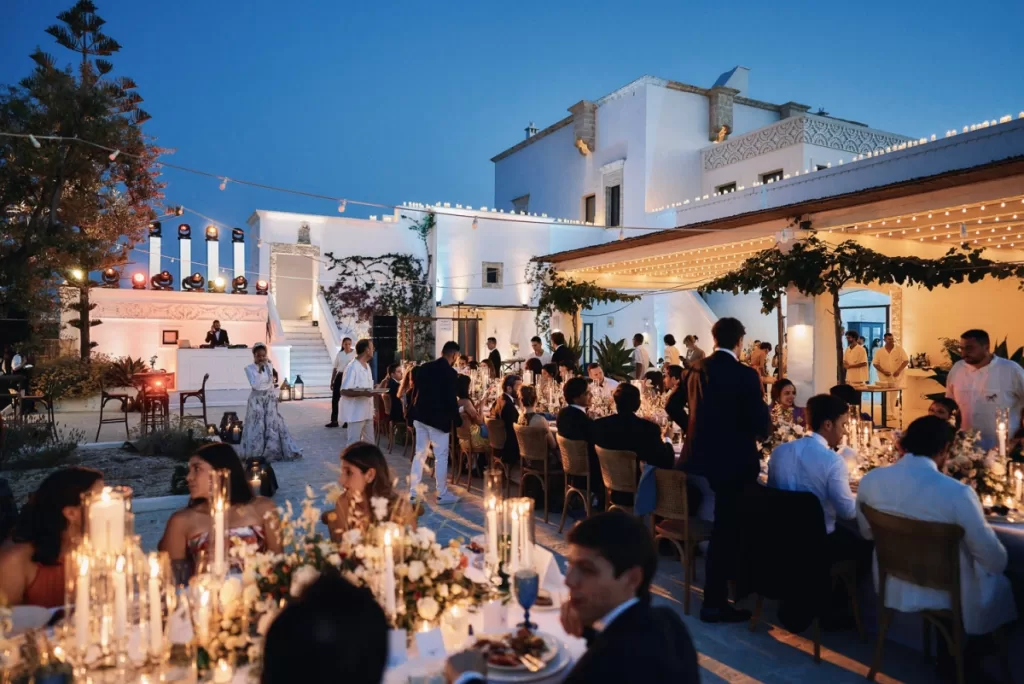 Guests dining under string lights during a summer wedding evening at Masseria Calderisi