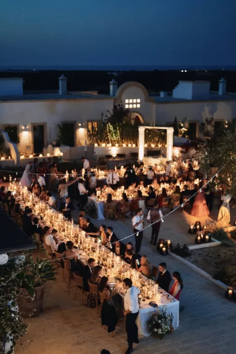 Wide view of candlelit courtyard dinner under the stars at Masseria Calderisi
