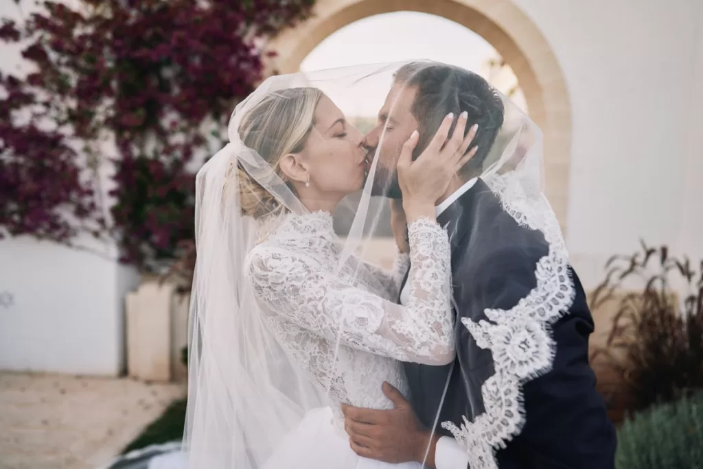 Bride and groom share a romantic kiss under the veil at Masseria Calderisi