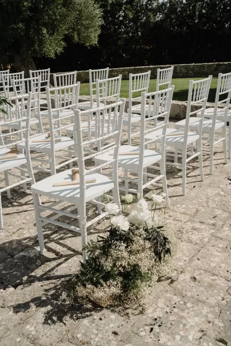 Rows of white chairs and floral arrangements ready for the outdoor ceremony at Masseria Monitilli.