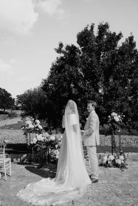 The couple exchange vows surrounded by trees and florals in the outdoor ceremony space at Masseria Monitilli.
