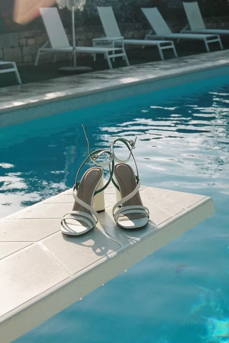 The bride’s block-heel sandals resting on a diving board beside the pool at Masseria Monitilli.