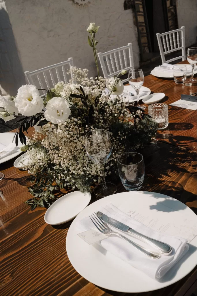 Elegant table setting with baby's breath and lisianthus flowers on wooden tables at Masseria Monitilli.