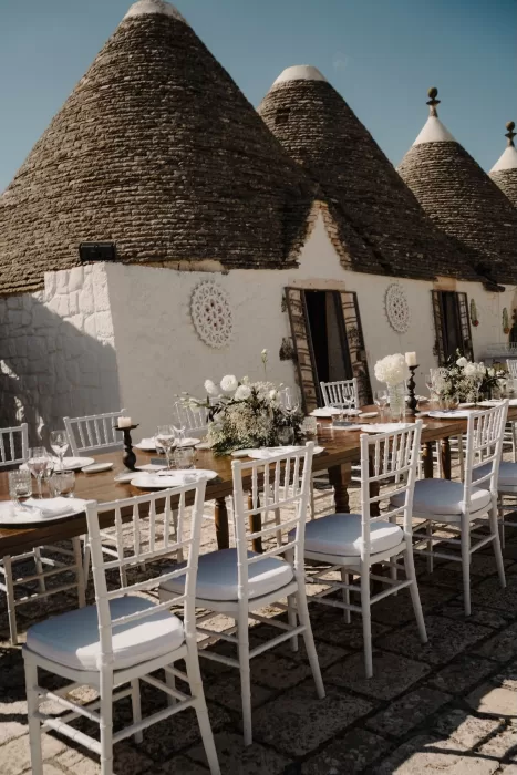 Wedding reception setup in front of Masseria Monitilli’s iconic trulli rooftops, styled with white florals and rustic charm.