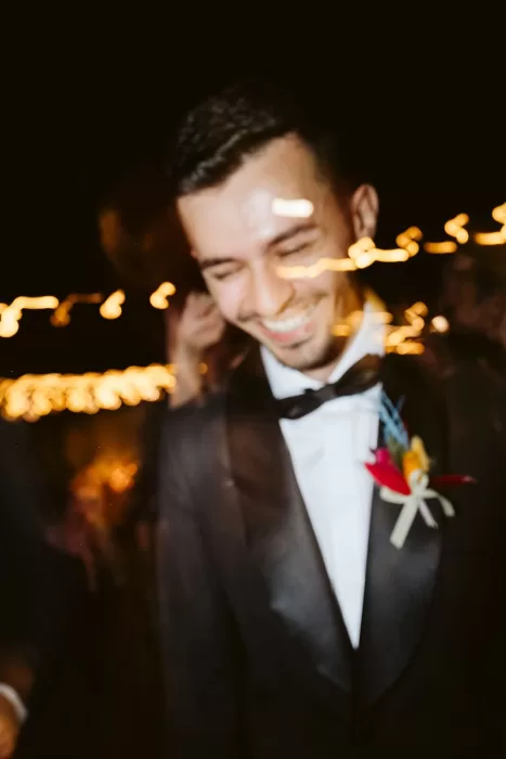 Joyful groom dancing under string lights during nighttime wedding celebrations at Masseria Spina