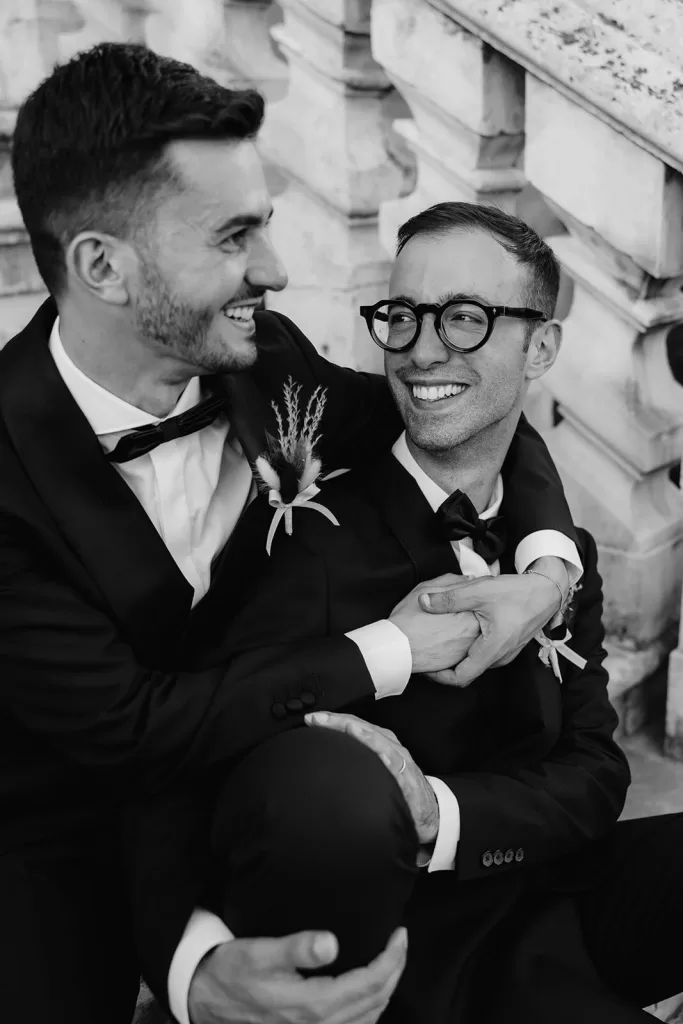 Joyful candid of the grooms embracing on the steps of Masseria Spina