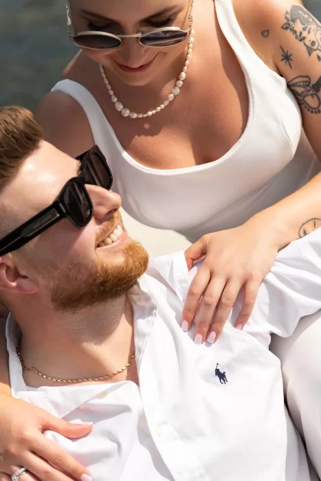 Stylish couple relaxing on a boat, smiling at each other under the sun at Parco Civico Teresio.