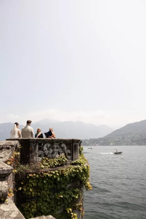 Intimate wedding ceremony on a stone terrace draped in ivy, overlooking Lake Como at Parco Civico Teresio.