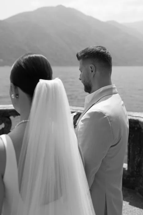 Bride and groom sharing a quiet moment by the lake at Parco Civico Teresio, with mountain scenery in the background.