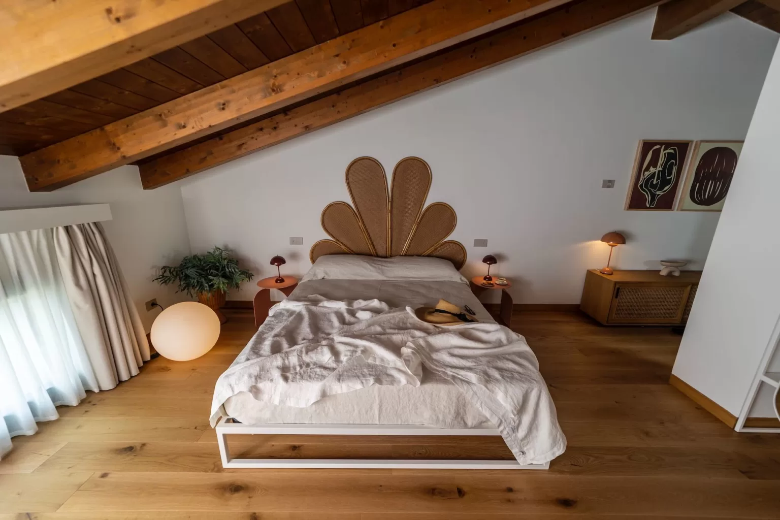 A designer bedroom at Villa Agavi with a sculptural rattan headboard and warm wood accents, perfect for a chic wedding stay.