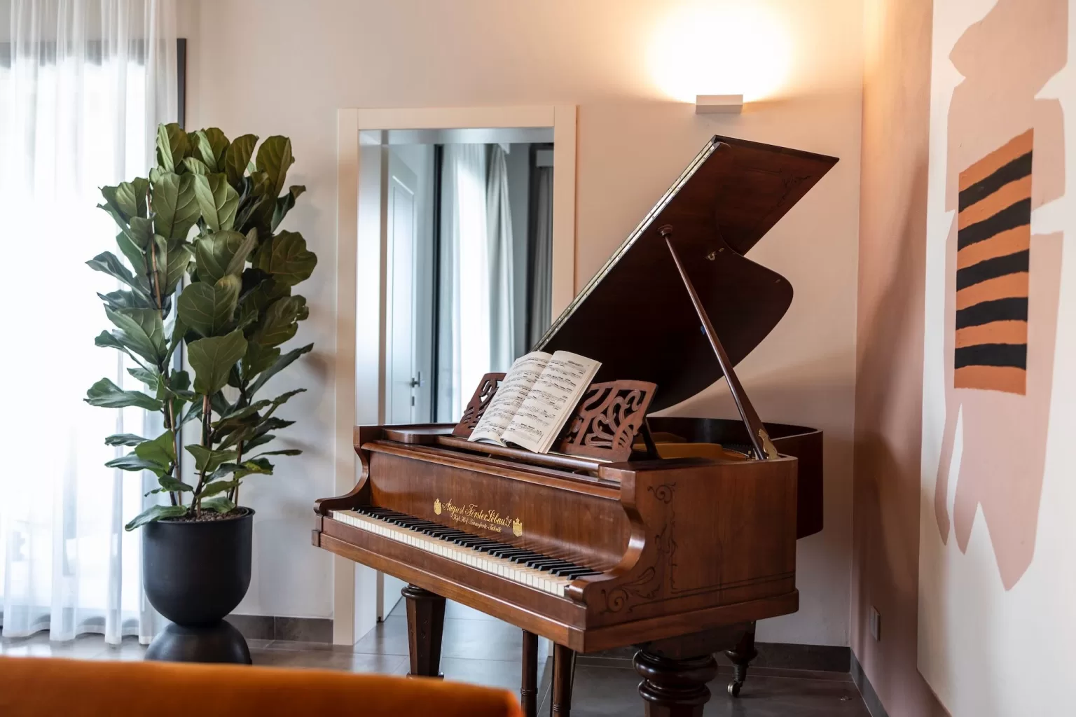 A vintage grand piano stands in a light-filled corner of Villa Agavi, perfect for romantic wedding music and intimate moments.