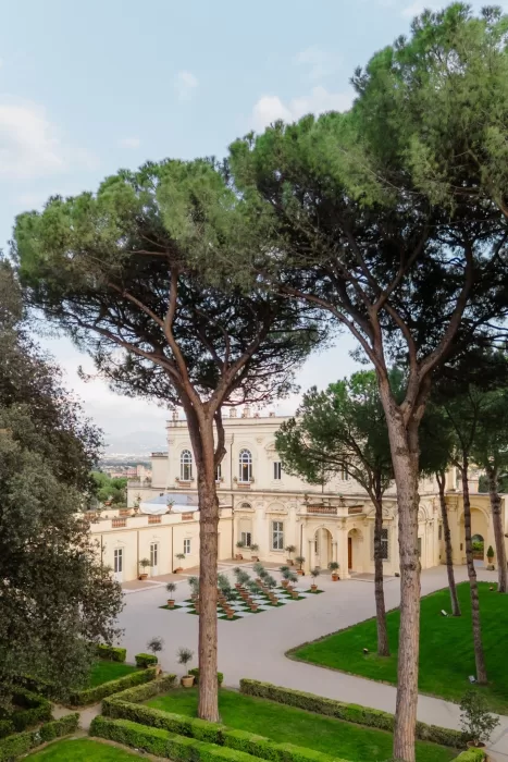Grand entrance of Villa Aurelia framed by tall umbrella pines and manicured gardens