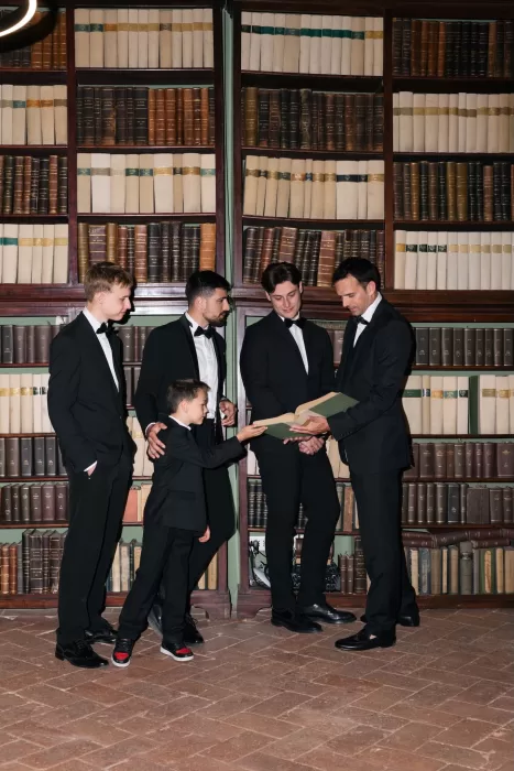The groom and groomsmen share a lighthearted moment in an old-world library at Villa Medicea di Lilliano.