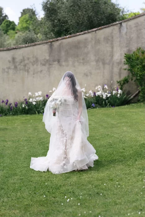 Bride walking gracefully across the garden lawn with her veil billowing, surrounded by irises at Villa Medicea di Lilliano.