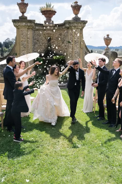 Joyful confetti moment as newlyweds walk through cheering guests on the lawn at Villa Medicea di Lilliano.