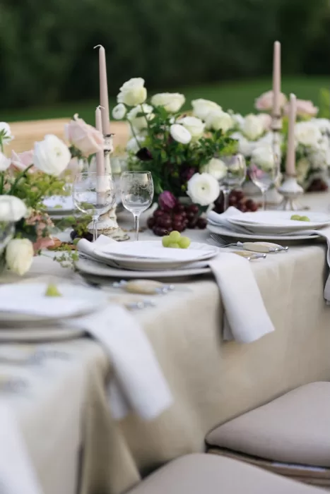Close-up of romantic wedding table with white roses, grapes, and taper candles at Villa Medicea di Lilliano.