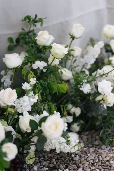 Elegant floral arrangement with white roses and wild greenery on pebbled ground at Villa Medicea di Lilliano.