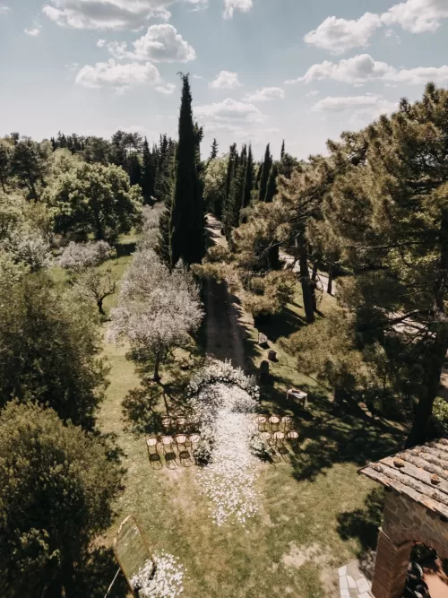 Aerial view of the intimate outdoor wedding ceremony space at Villa Olimpia with white floral décor and curved chair setup.