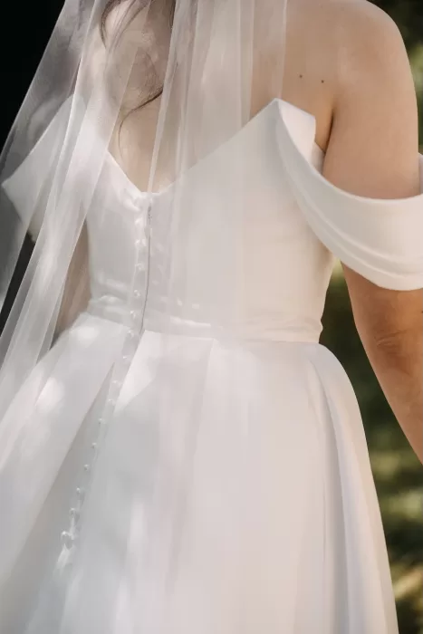 Close-up of bride’s off-shoulder gown and buttons down the back at Villa Olimpia