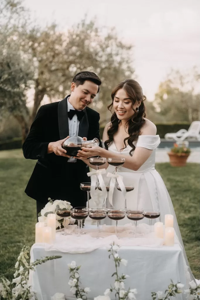Bride and groom pour espresso martinis into a champagne tower during their Villa Olimpia reception