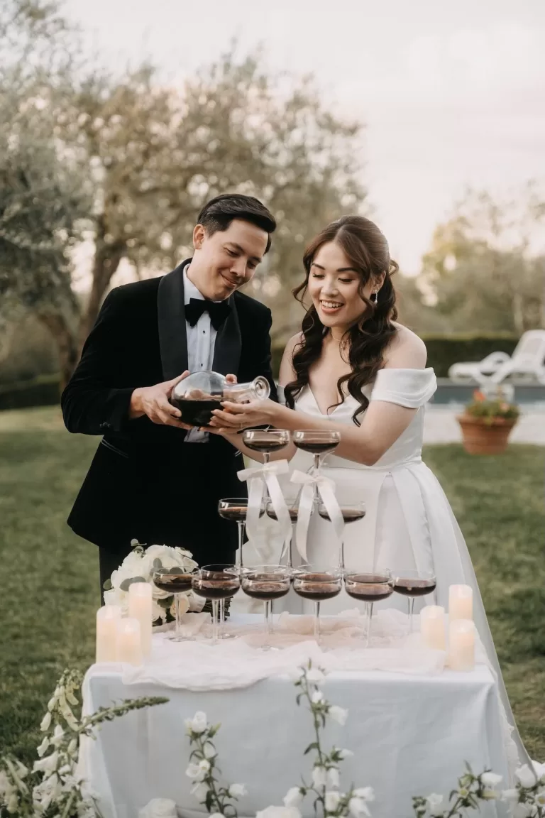 Bride and groom pour espresso martinis into a champagne tower during their Villa Olimpia reception
