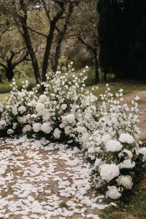 Close-up of white floral arrangements and scattered petals lining the aisle at Villa Olimpia