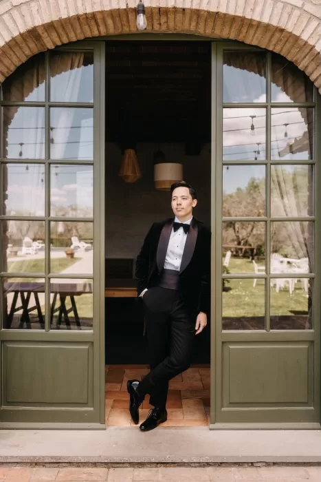 Groom stands confidently in arched doorway of Villa Olimpia before the ceremony