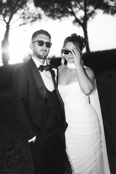 Cool and confident newlyweds in sunglasses pose together at sunset in the gardens of Villa Ravano.