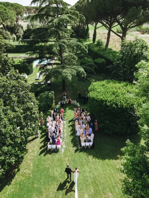Bride walking down the aisle with her father through a lush garden setting at Villa Ravano.