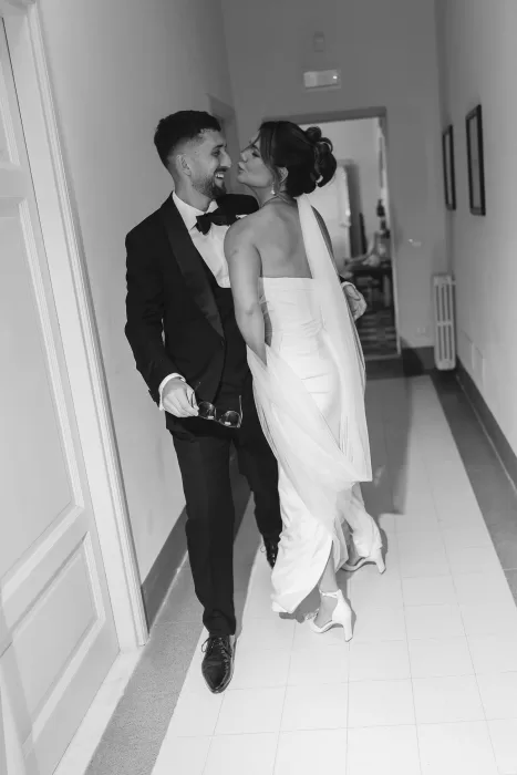 Playful moment between the newlyweds as they walk down a sunlit hallway at Villa Ravano.