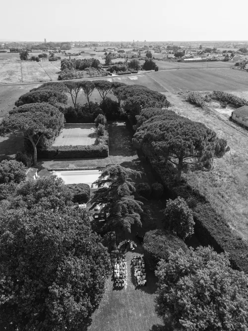 Aerial black-and-white shot of Villa Ravano’s ceremony setup surrounded by countryside and gardens.