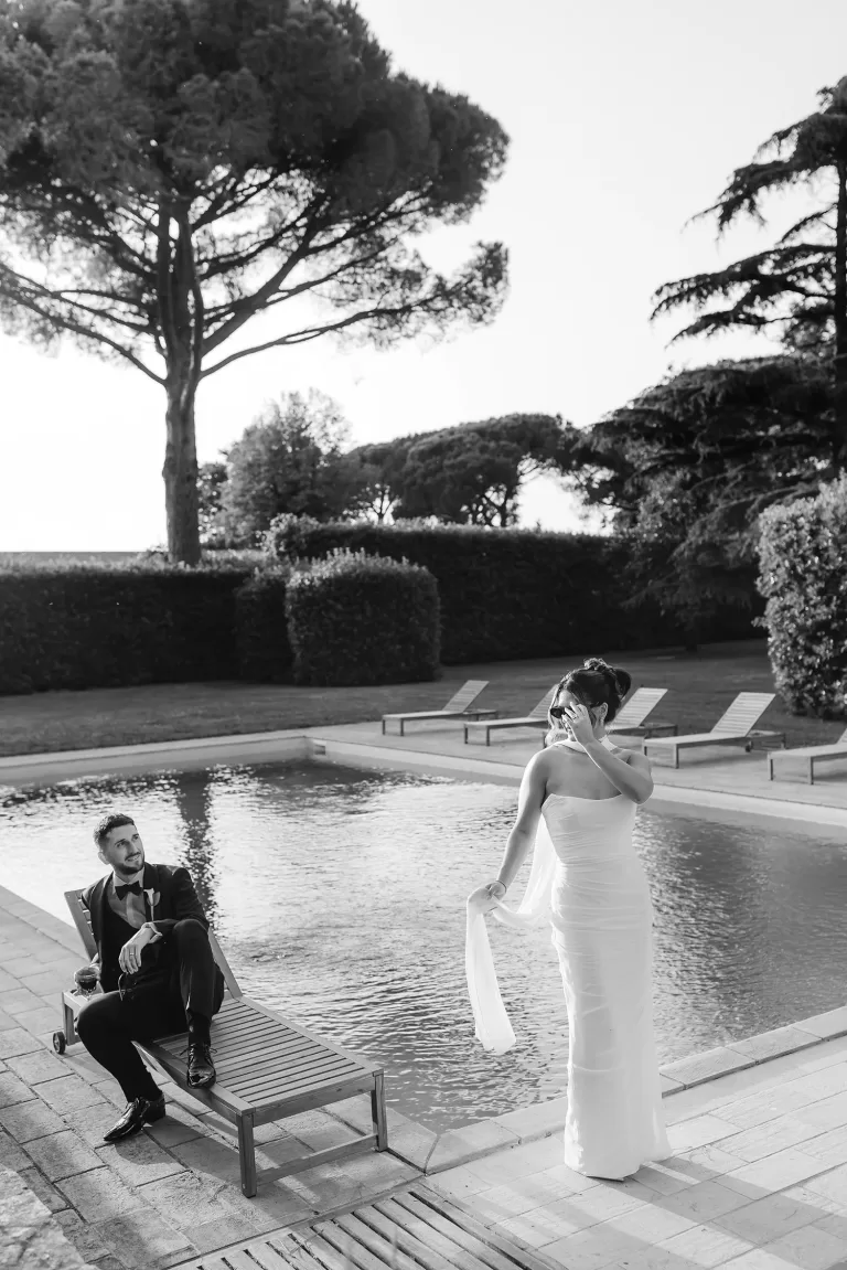 Bride and groom share a quiet moment by the pool at Villa Ravano, captured in timeless black and white.