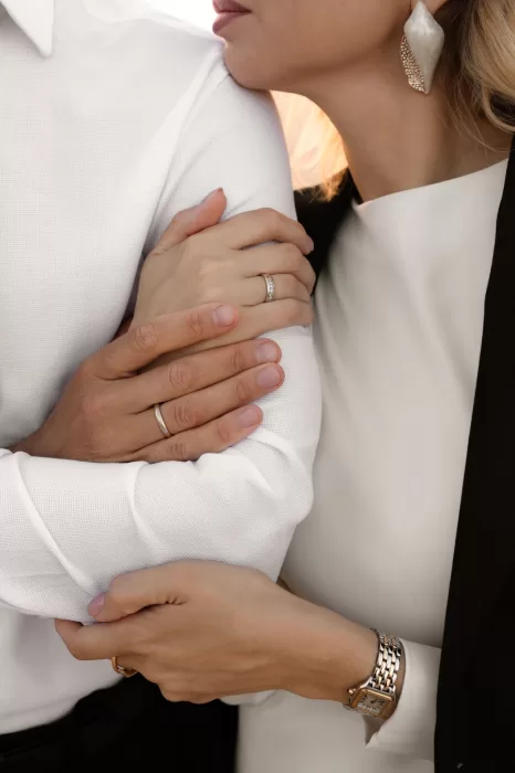 A close-up of the couple’s intertwined arms, showcasing their wedding rings and an intimate, affectionate pose.