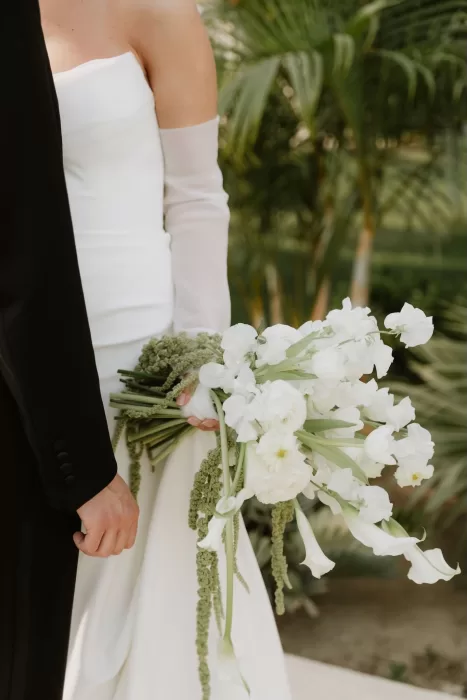 Bride and groom standing together holding white cascading bouquet at Baja Luna.
