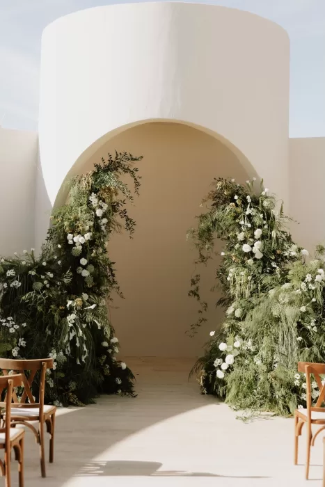 Wedding ceremony viewed through a curved white archway at Baja Luna’s open-air chapel.