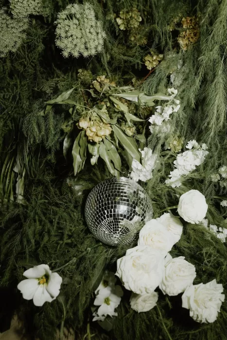 Disco ball nestled among white roses and greenery at Baja Luna wedding reception.