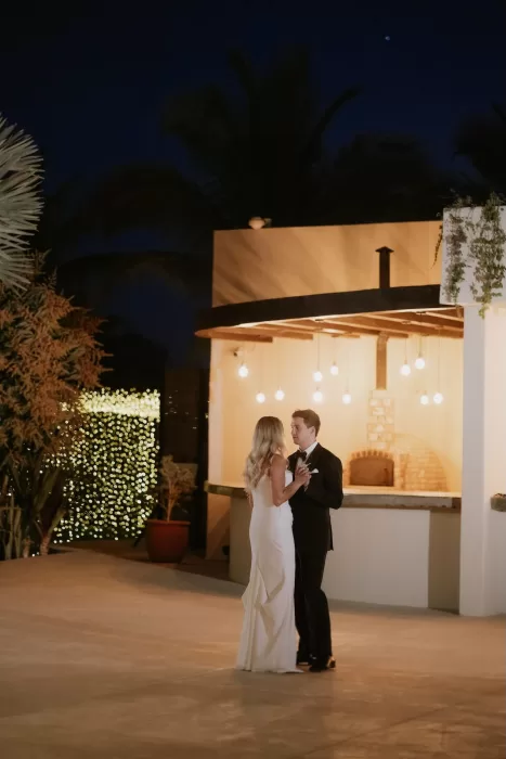 Bride and groom sharing first dance under evening lights at Baja Luna.